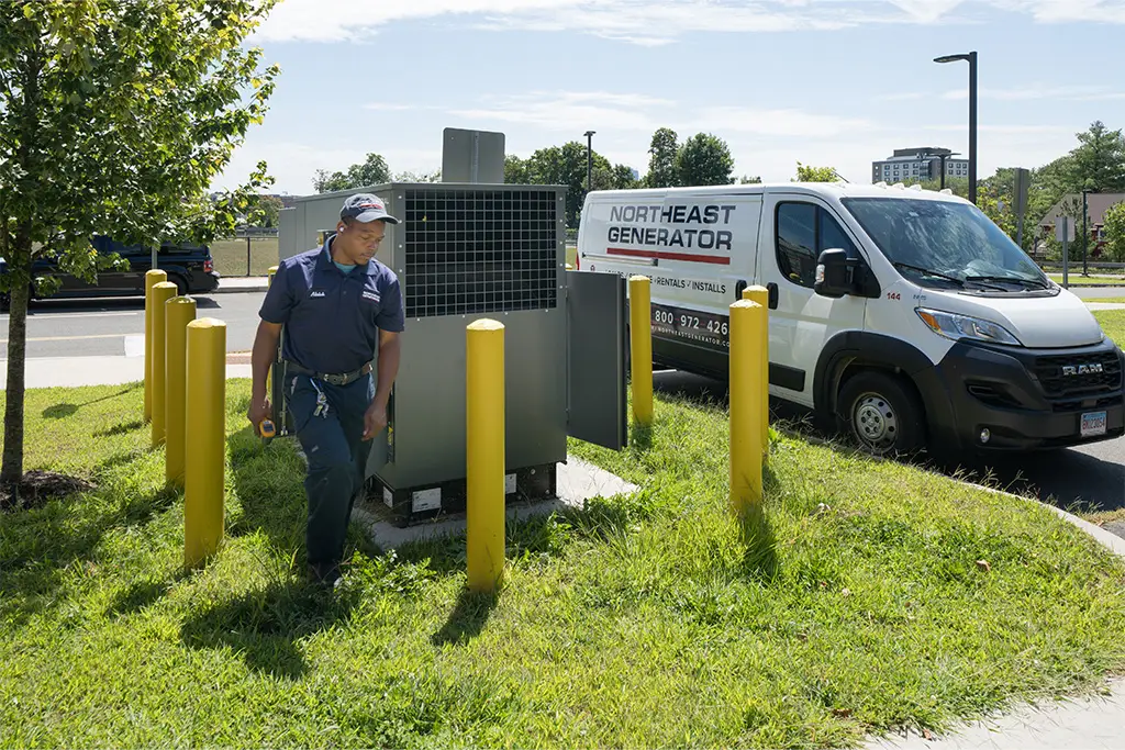 Technician at a commercial generator site with a Northeast Generator van