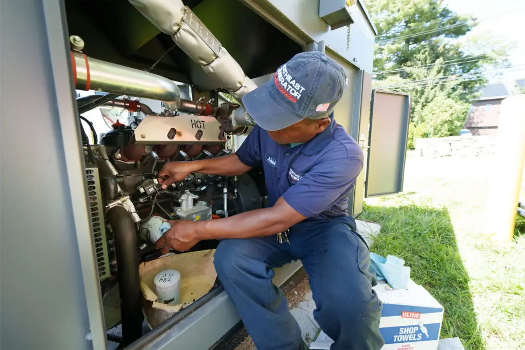 Technician servicing the engine inside a commercial generator enclosure