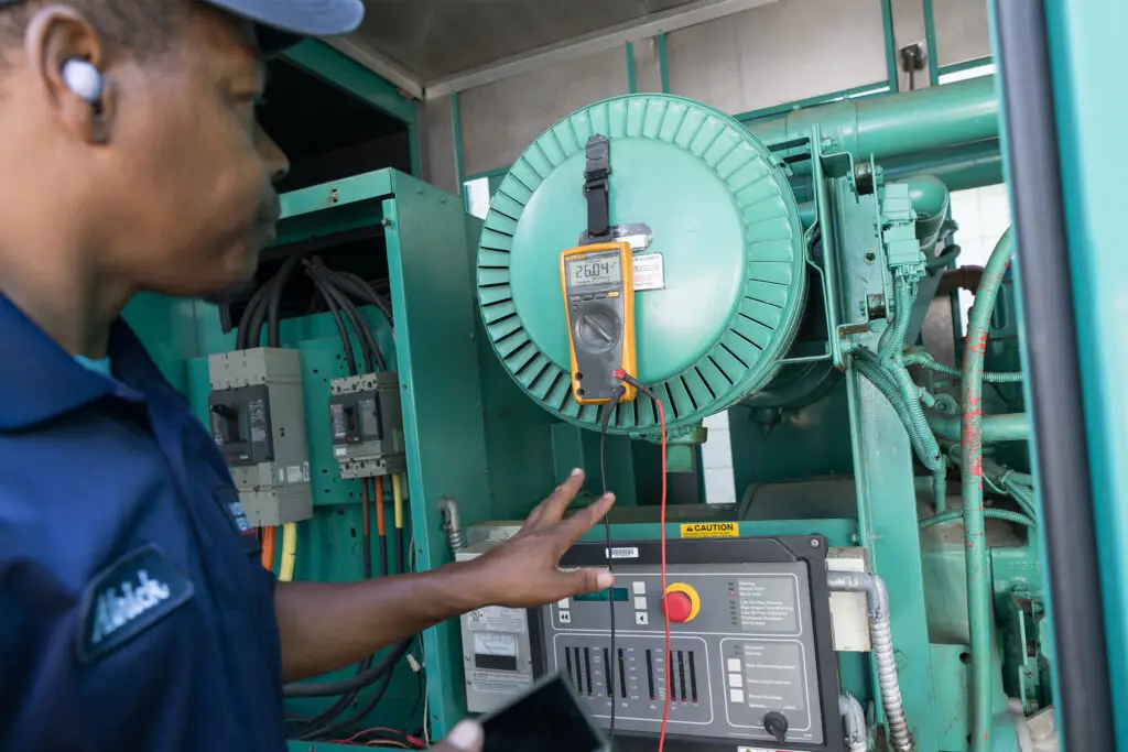 Technician testing a commercial generator control panel with a multimeter