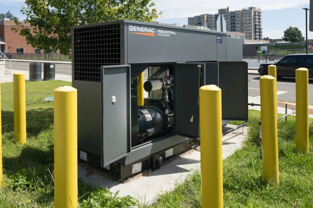 Generac Industrial Power commercial generator with yellow bollards on a city site