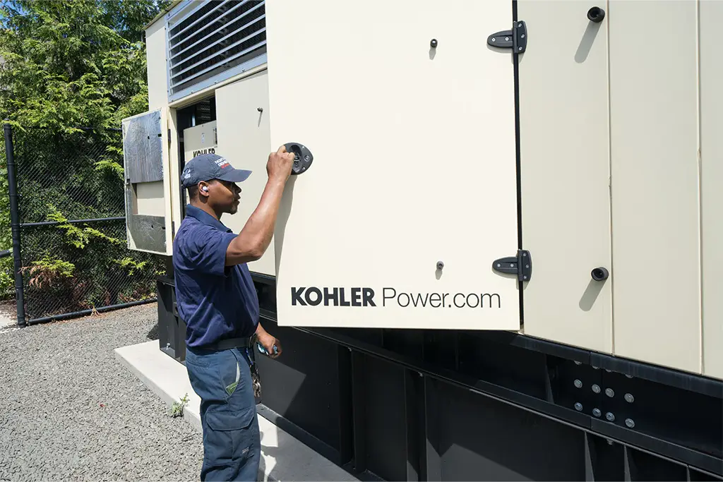 Technician opening the enclosure of a Kohler commercial generator